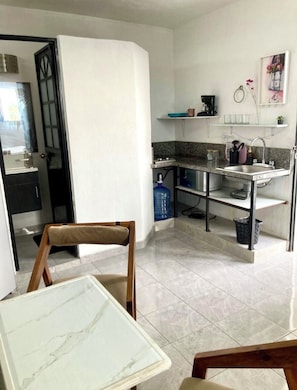 Cuina compacta amb zona de dinar, dispensador d'aigua i un rentaplat.