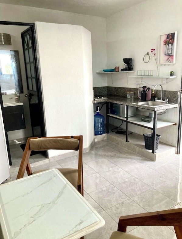 A compact kitchen with a dining area, a water dispenser, and a sink.