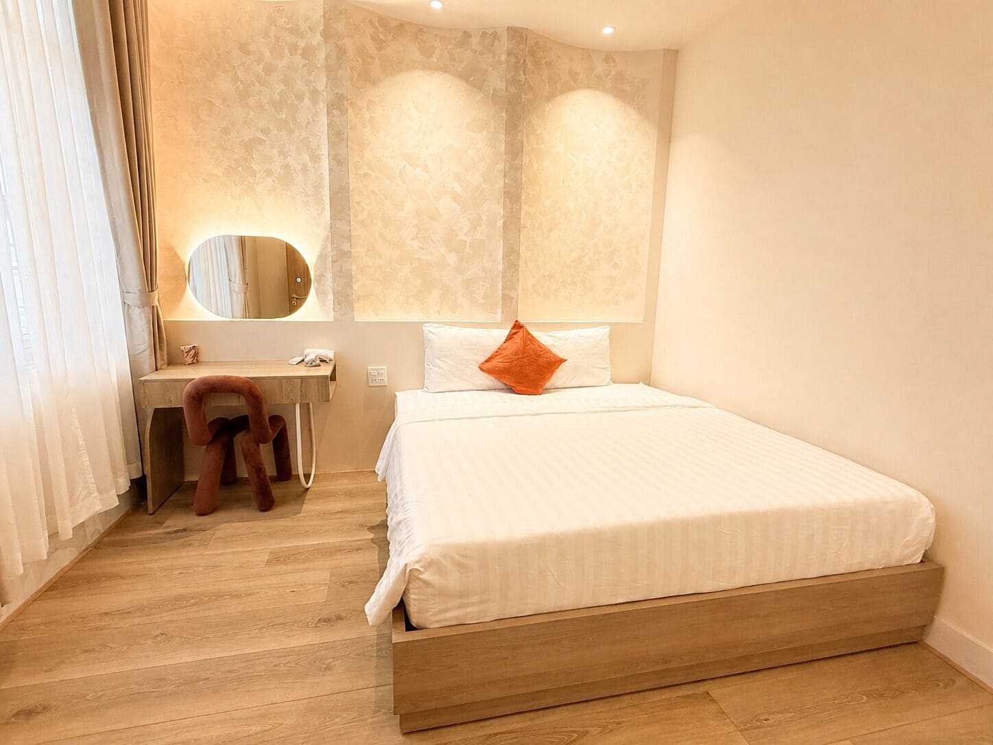 A hotel room with a wooden bed, a desk, and a mirror.