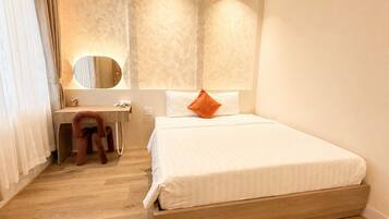 A hotel room with a wooden bed, a desk, and a mirror.