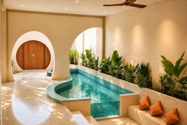 A swimming pool with a curved edge, surrounded by plants and a wooden door.