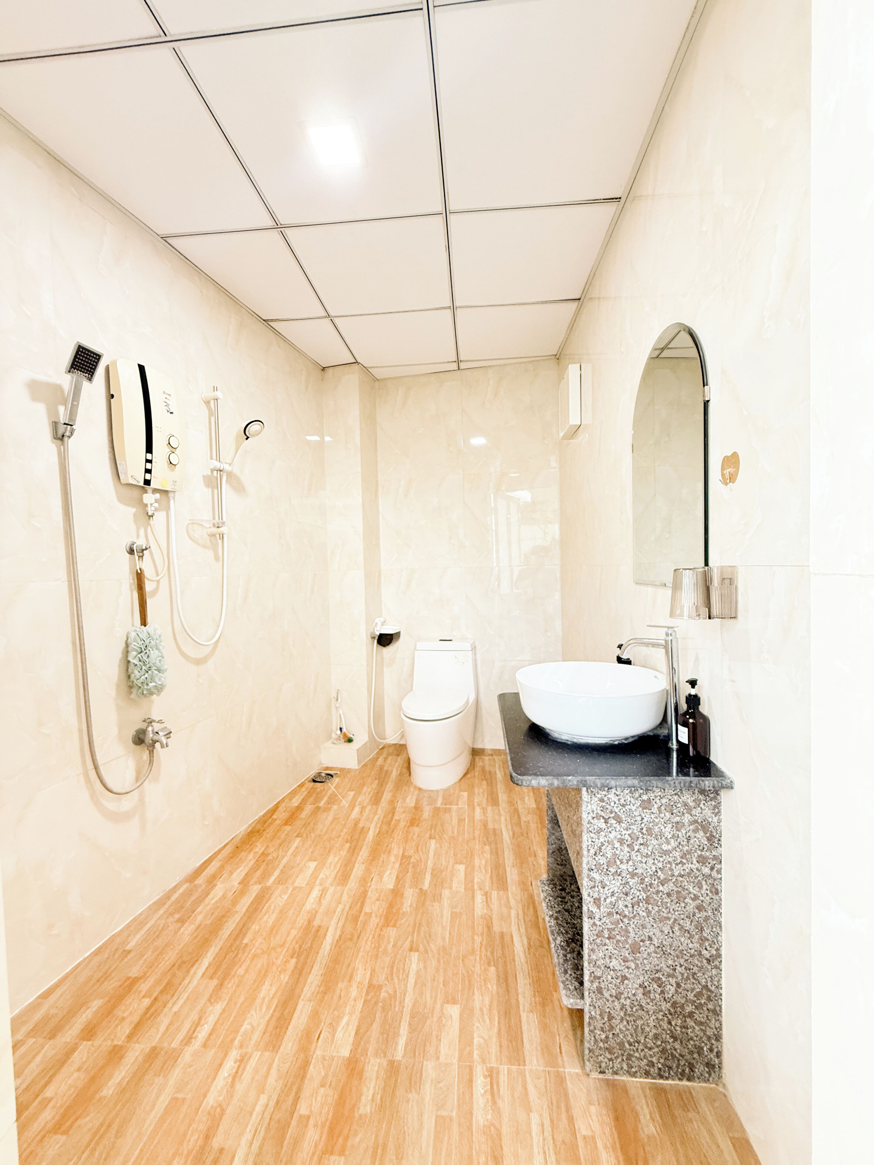 A bathroom with a toilet, sink, shower, and mirror.