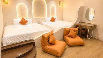 A hotel room with two beds, a desk, a mirror, and a staircase.