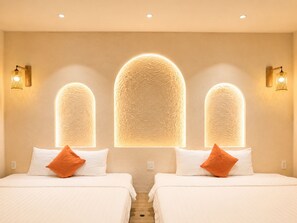 Une chambre d’hôtel avec deux lits, chacun doté de draps blancs et d’oreillers orange, et un mur orné de trois panneaux lumineux.