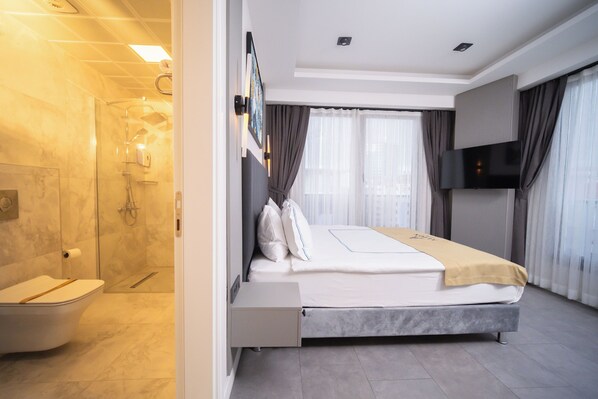 A modern hotel room with a shower, a bed, a TV, and a window with curtains. - Alion Hotel Izmir (Izmir)