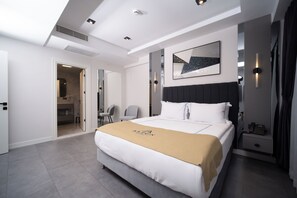 A modern hotel room with a large bed, a bedside table with a phone, a wall-mounted artwork, and a door leading to a bathroom. - Alion Hotel Izmir (Izmir)