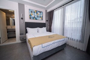 A modern hotel room with a bed, a large window with sheer curtains, a painting on the wall, and a bathroom visible through an open door. - Alion Hotel Izmir (Izmir)