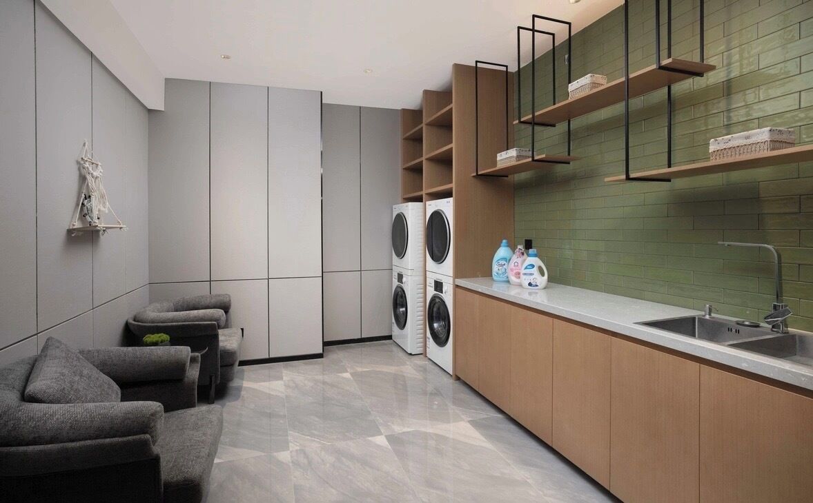 Una cocina moderna con electrodomésticos integrados, un sofá gris y un pequeño comedor.