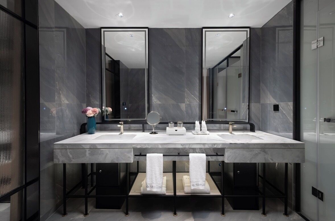 Un baño moderno con lavamanos doble, espejos grandes y un perchero para toallas.