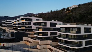 A modern residential building with multiple balconies and a flat roof.