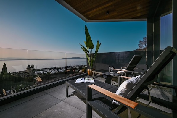 A modern outdoor seating area with a view of a marina and distant mountains.