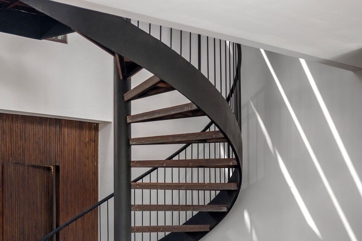 Eine Wendeltreppe mit Holzausstattung und Metallgeländern, die zu einer oberen Ebene führt.
