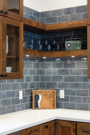 A kitchen with dark blue tiles, wooden cabinets, and a green radio on the shelf. - Secluded Lakefront Retreat on 14 Acres with Private Boathouse & Firepit (St. Germain)