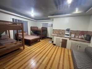 Une chambre avec des lits superposés, un coin cuisine et un sol à motifs.
