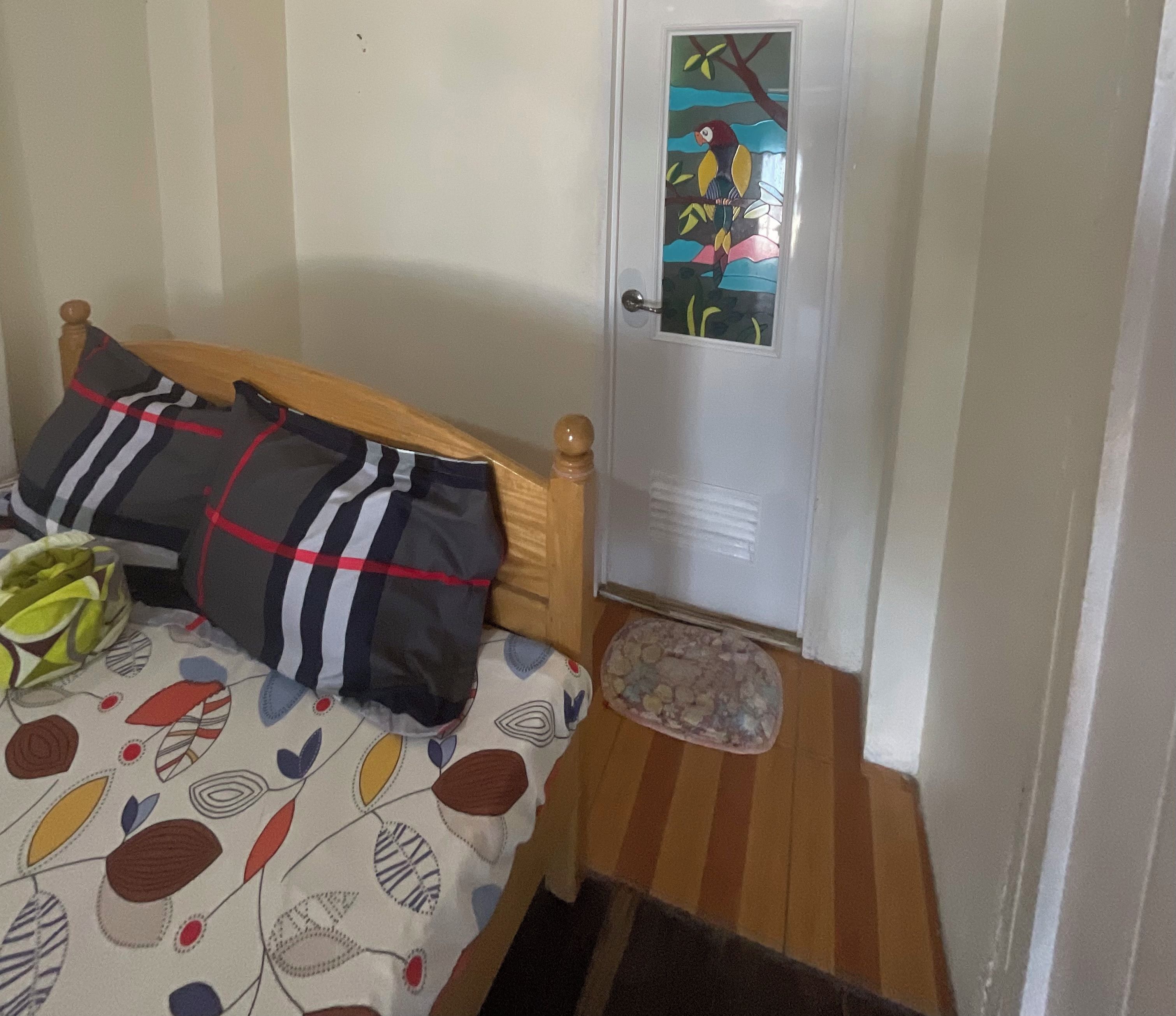 Ett sovrum med en säng, kuddar, en djursäng och en dörr med ett fönster.
