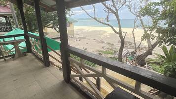 A covered outdoor area with a view of a beach and ocean.