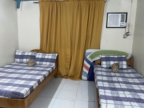 A room with two single beds, a window with curtains, a wall-mounted air conditioner, and a tiled floor. - Diva Sunrise Beach Resort (Dipaculao)