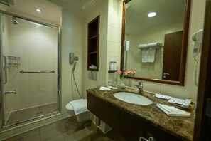 A hotel bathroom with a glass shower enclosure, a marble sink, and a large mirror. - Saja by Warwick, Makkah (Makkah)