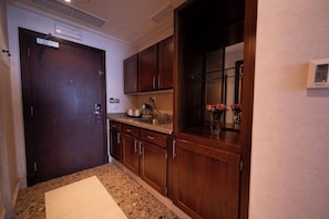 A kitchen with wooden cabinets, a granite countertop, and a built-in oven. - Saja by Warwick, Makkah (Makkah)