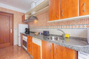A kitchen with wooden cabinets, a stainless steel sink, and a tiled backsplash.