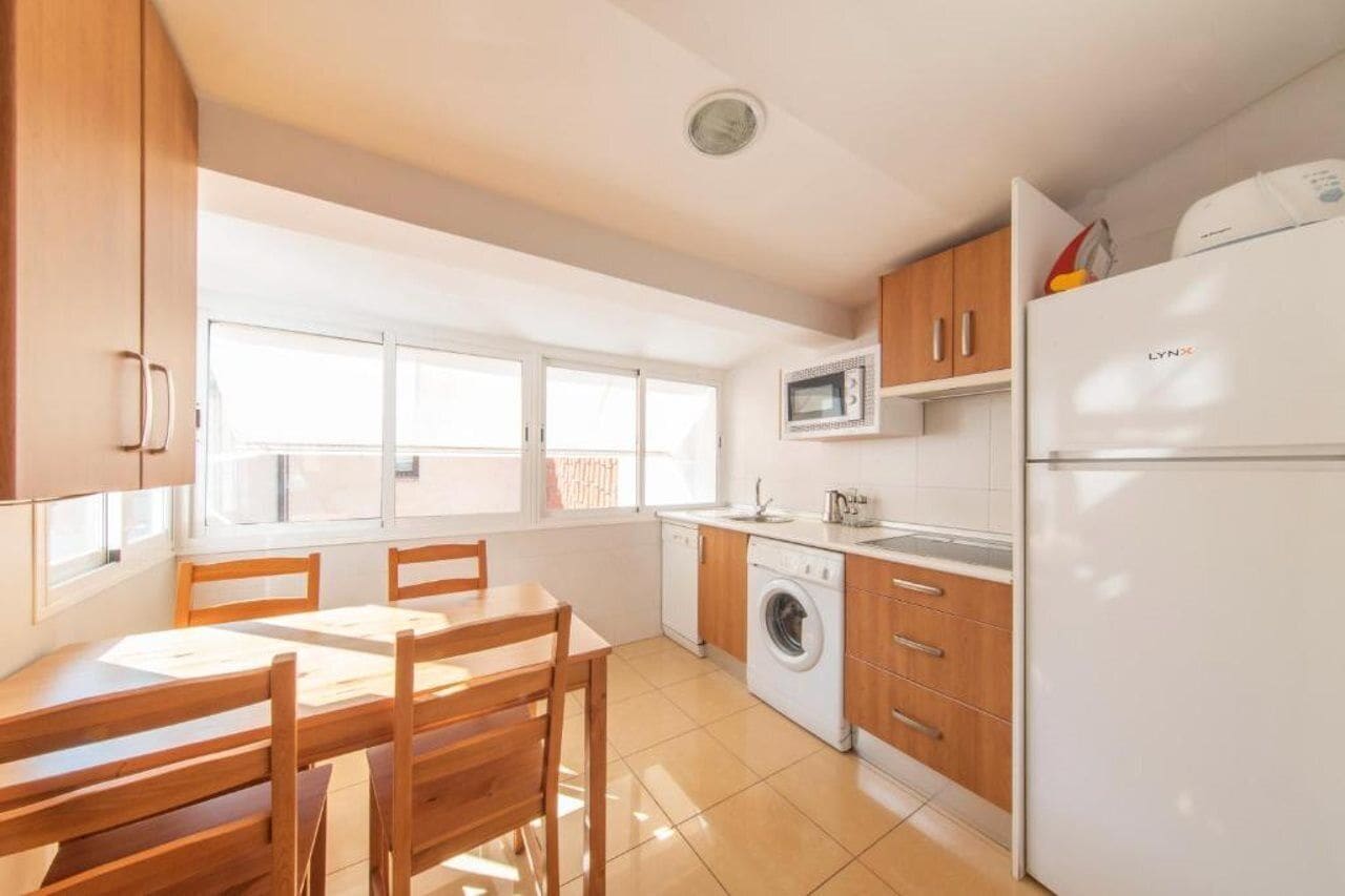 Cocina compacta con lavadora, microondas y refrigerador.
