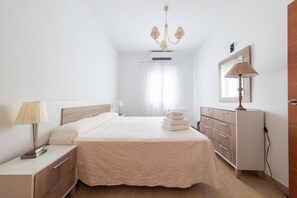Una habitación de hotel con cama, mesitas de noche, lámpara, cómoda y espejo.