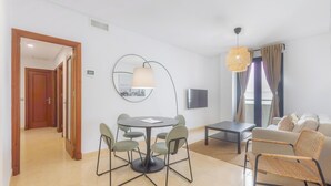 A modern living room with a round dining table, chairs, a sofa, and a TV.
