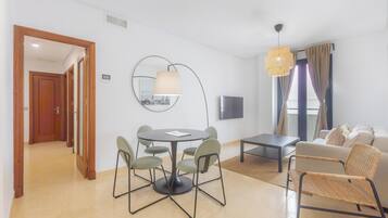 Una sala de estar moderna con una mesa de comedor redonda, sillas, un sofá y un televisor.