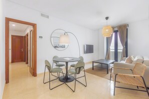 A modern living room with a round dining table, chairs, a sofa, and a TV.