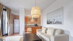 A modern living room with a sofa, a coffee table, and a kitchen area in the background.