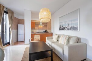 Una sala de estar moderna con un sofá, una mesa de centro y una cocina al fondo.
