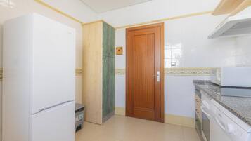 Una cocina con un refrigerador blanco, una puerta de madera, un microondas y un lavavajillas.
