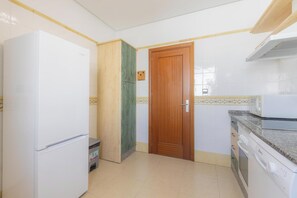 Una cocina con un refrigerador blanco, una puerta de madera, un microondas y un lavavajillas.