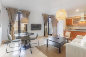 A modern living room with a round dining table, a sofa, and a kitchen area with a counter and cabinets. - Apt Blueseas Bahia Marina (El Puerto de Santa Maria)