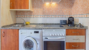A compact kitchen with a washing machine, a coffee maker, and a microwave.