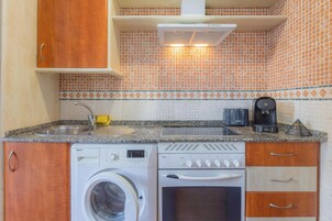 Una cocina compacta equipada con lavadora, tostadora y cafetera.