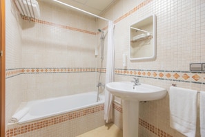 A bathroom with a bathtub, a sink, and a mirror. - Apt Blueseas Bahia Marina (El Puerto de Santa Maria)
