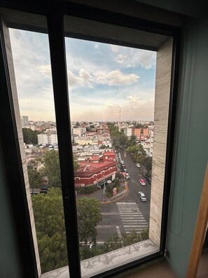 Vista desde una ventana sobre un paisaje urbano con edificios, calles y cielo despejado.