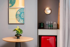 A modern hotel room with a round table, a vase with flowers, a red minibar, and wall-mounted artwork. - Pagoda Hotel Chongqing Incity Hualongqiao Station (Chongqing)