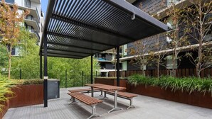 An outdoor patio area with a covered seating arrangement and planters. - Mountain View 1BR Retreat in Braddon (Braddon)