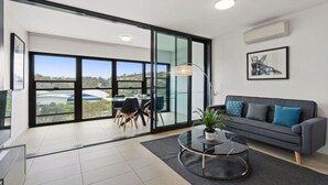 A modern living room with a sofa, a coffee table, and a dining area with chairs. - Mountain View 1BR Retreat in Braddon (Braddon)