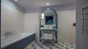 Un baño con bañera, tocador con espejo y perchero para toallas.
