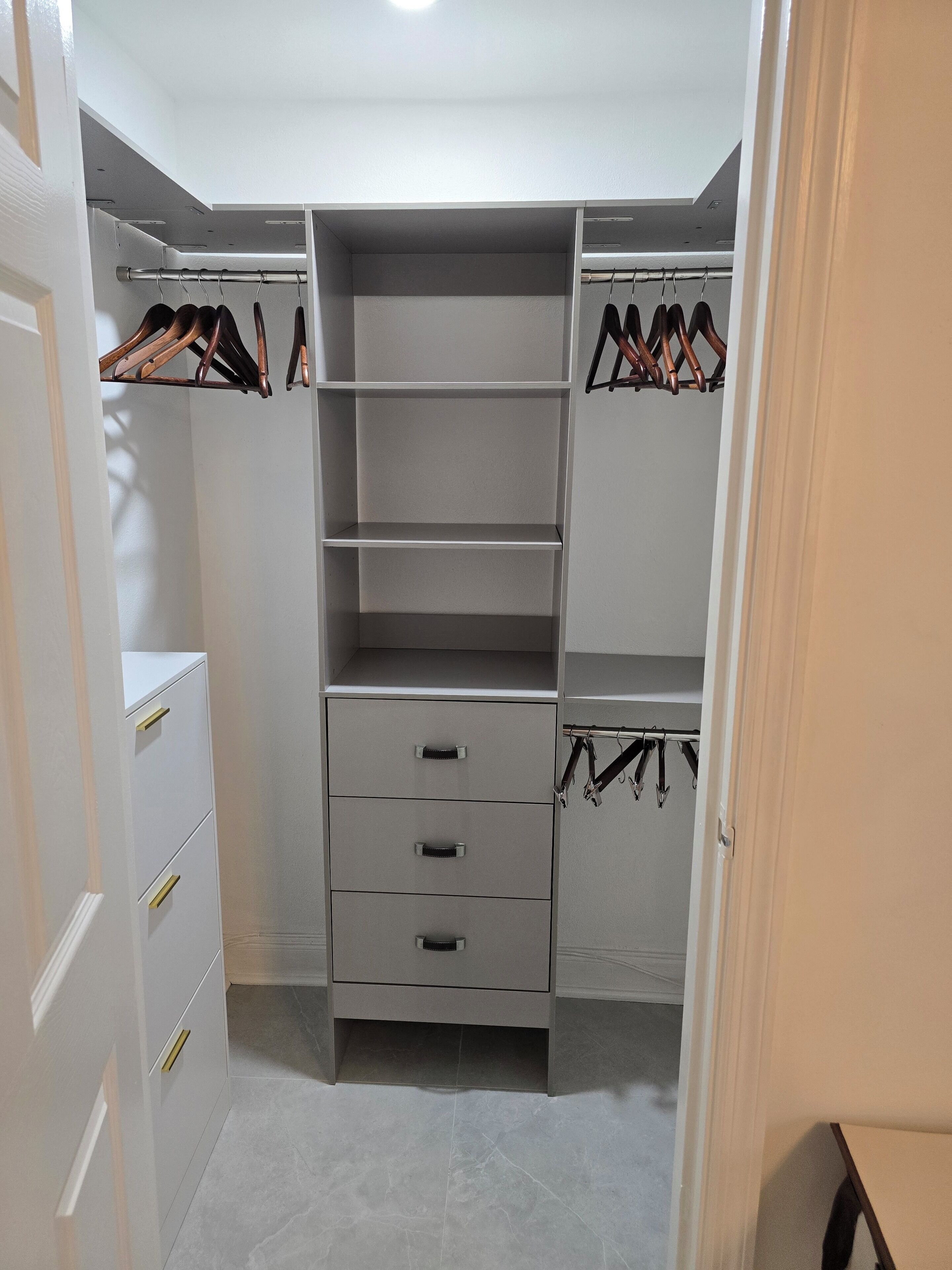 Un vestidor amplio con estantes abiertos, cajones y espacio para colgar.
