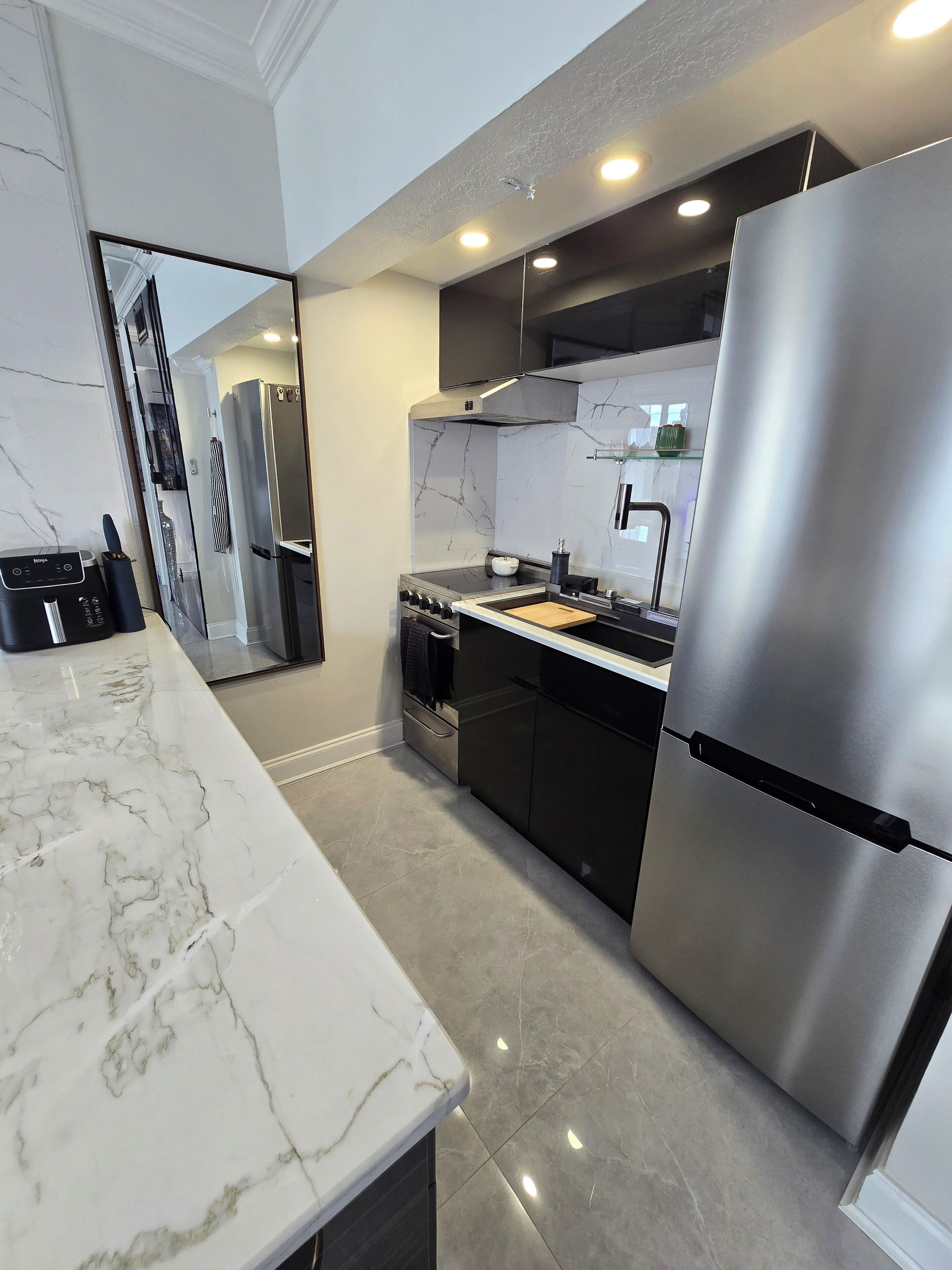 Cozinha moderna com bancada de mármore, eletrodomésticos de aço inoxidável e forno embutido.