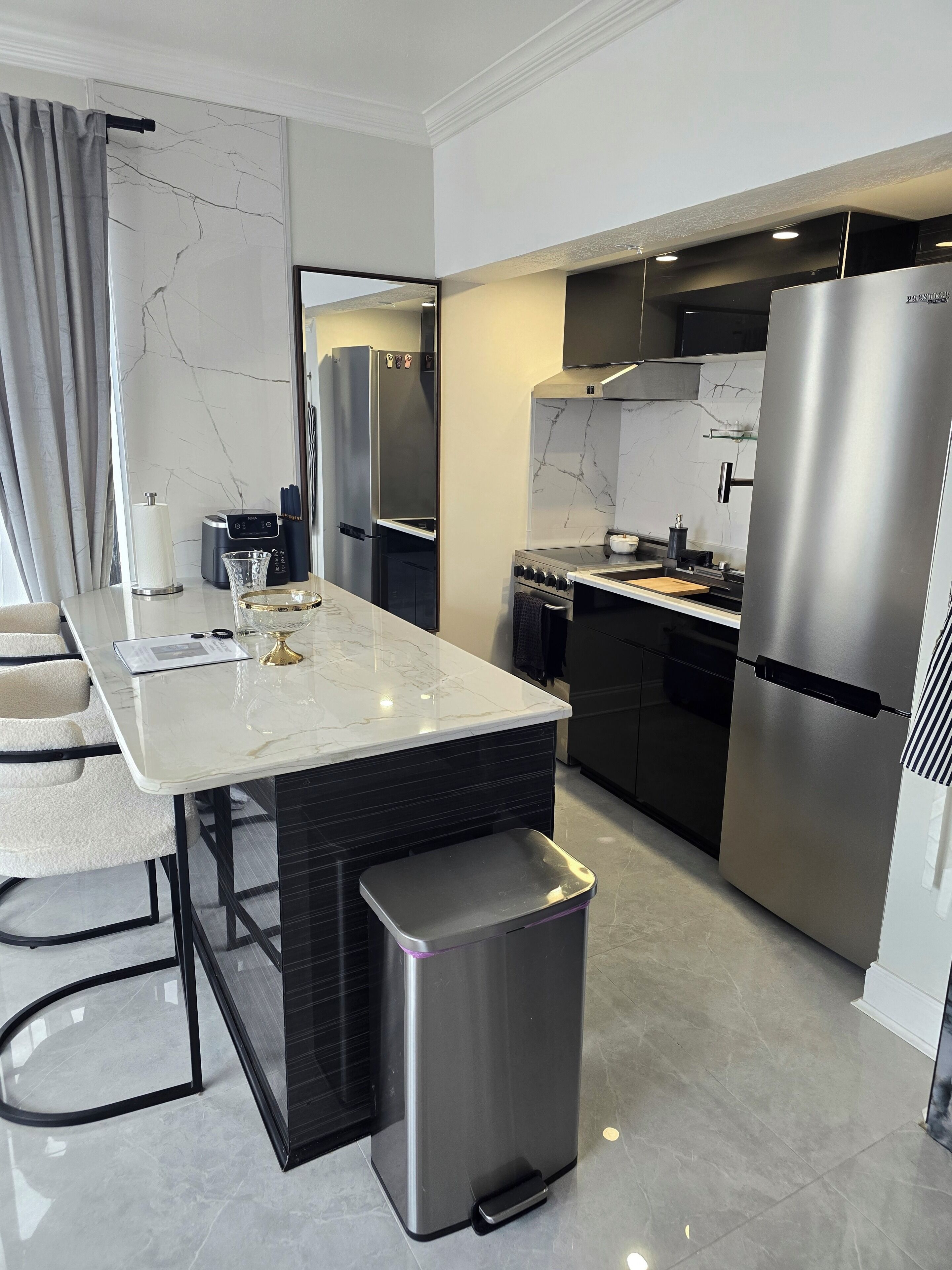 A modern kitchen with a marble countertop, stainless steel appliances, and a built-in oven.