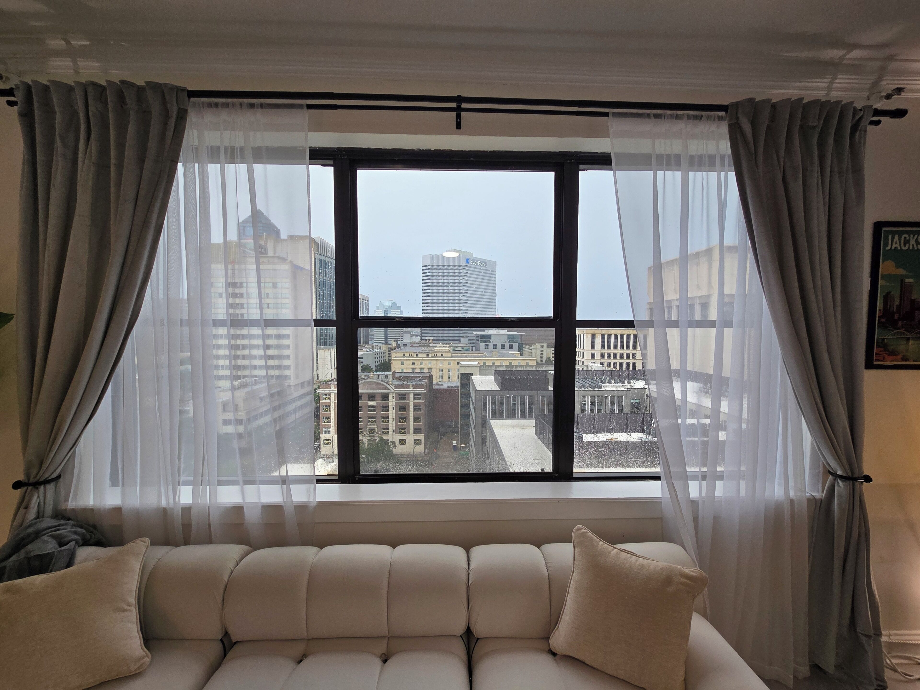 Una habitación con un ventanal, un sofá y cortinas.