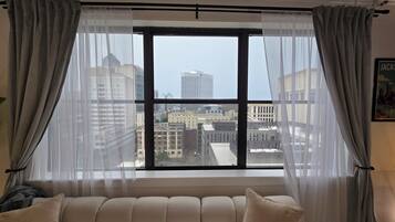Una habitación con un ventanal, un sofá y cortinas.