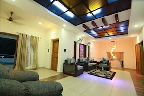 A living room with sofas, a coffee table, a ceiling fan, and a patterned rug.