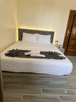 A neatly made bed with a grey headboard, white linens, and a brown towel. - Vista Pyramids Boutique Hotel (Giza)