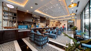 A modern bar area with seating and a bar counter, featuring geometric ceiling design and pendant lighting.